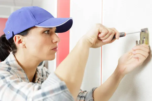young brunette woman repairs an electric socket with a screwdriver