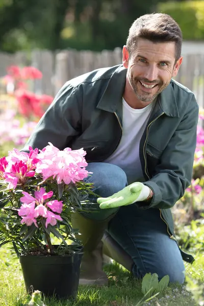 happy gardener in a greenhouse holding vases of flowers