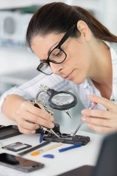 Woman Repairs Mobile Phone Looking Magnifying Glass — Stock Photo, Image