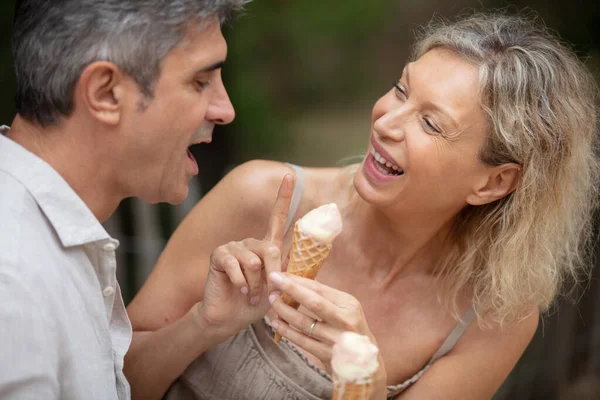 senior couple eating an ice cream on a bench