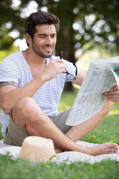 Mann Legt Sich Auf Grünes Gras Und Liest Zeitung — Stockfoto