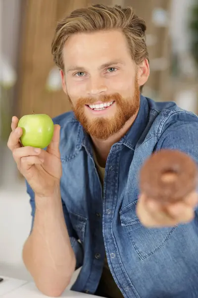 笑着拿着甜甜圈和苹果的男人 — 图库照片