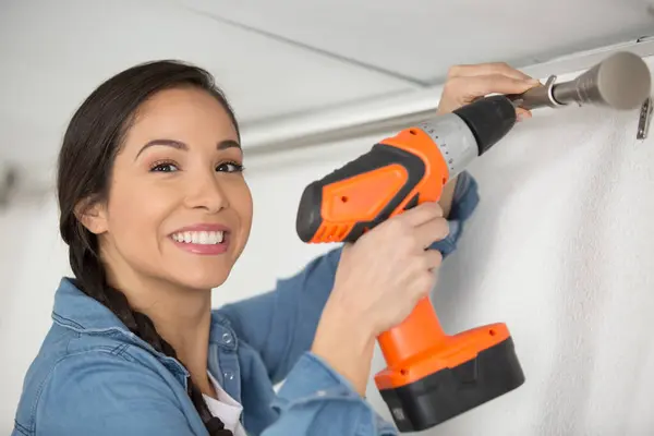 woman securing curtain rail support witha cordless drill