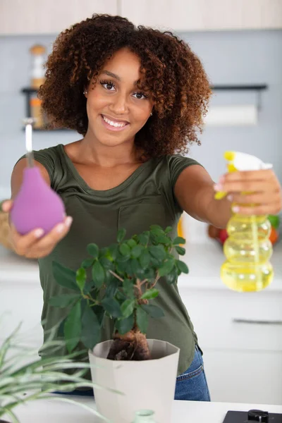 young attractive woman watering plants in home