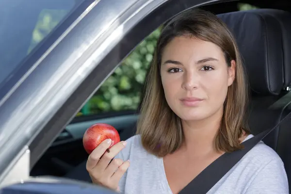 woman with an apple while driving the car