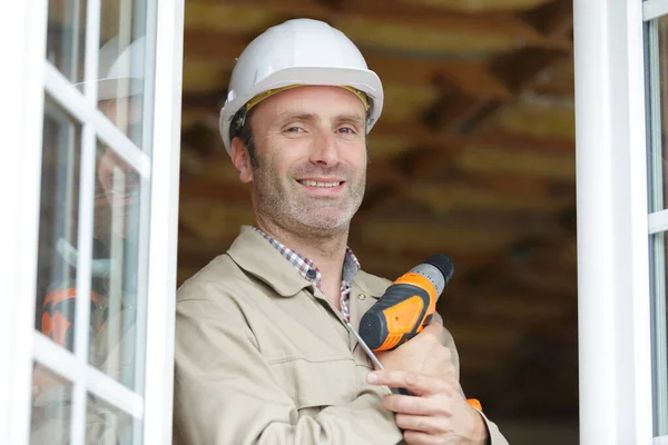 portrait of builder holding drill by double glazed windows