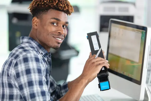 労働者は彼のコンピュータでオンラインで新しいカートリッジを注文します — ストック写真