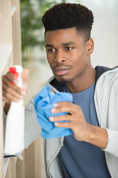 Mann Putzt Regal Mit Lappen Und Reinigungsmittel Der Wohnung — Stockfoto