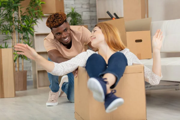 woman in cardboard box man is pushing around new home
