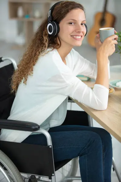 Stock image young woman in a wheelchair enjoying a cup of coffee