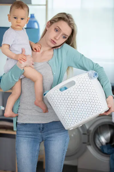 疲惫的年轻母亲和她的孩子一起洗衣服 — 图库照片