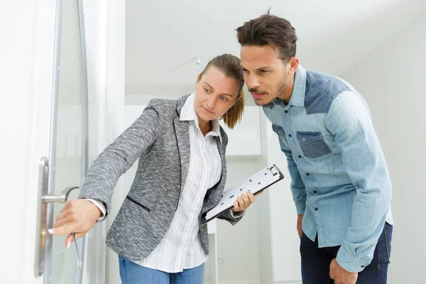 realtor pointing at door lock while visiting property with client