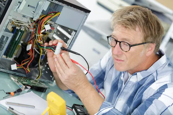 mature man fixing an old desktop computer using a screwdriver