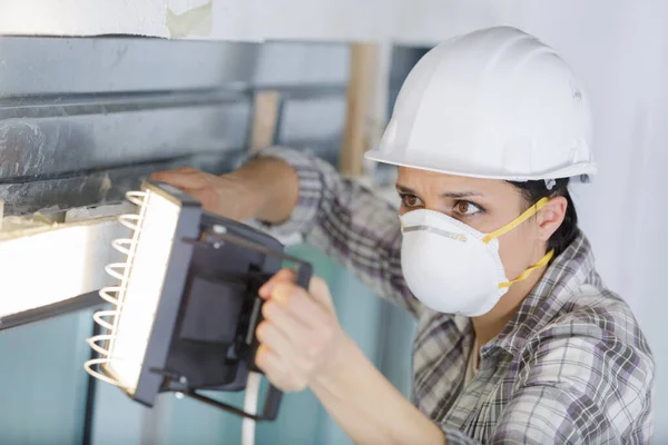 Bauarbeiterin Mit Maske Nutzt Beleuchtung Bei Der Arbeit — Stockfoto