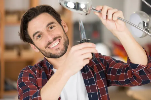 man using long nosed pliers on a standard lamp
