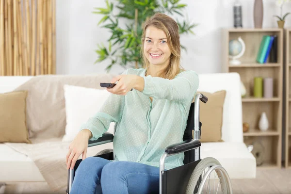happy disabled young woman in wheelchair watching tv