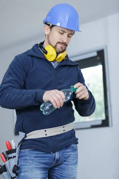 a male builder is drinking water