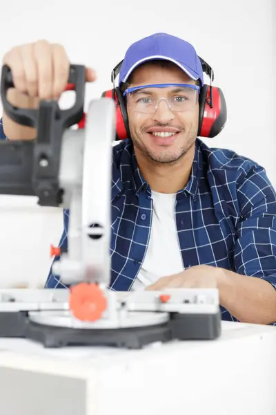 man using a circular saw wearing ear-defenders and goggles