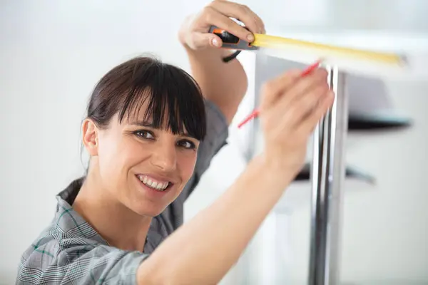 woman working on a kitchen installation using measuring tape
