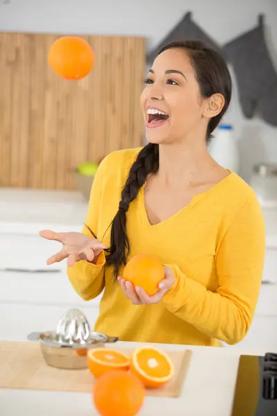 pregnant woman juggles oranges in the kitchen
