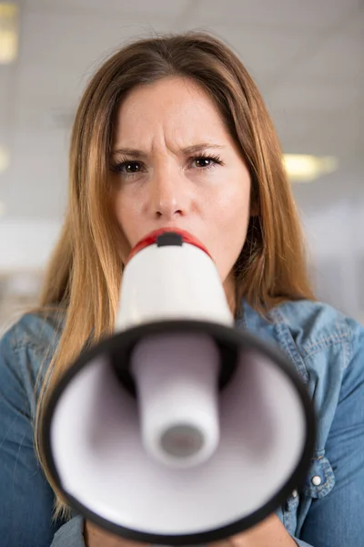 frowning woman speaking through a loud speaker