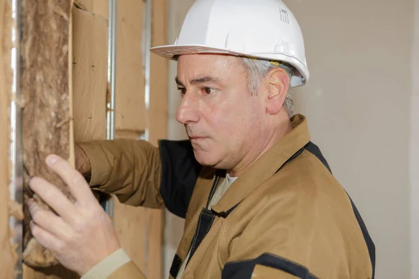 mature man fitting insulation into walls