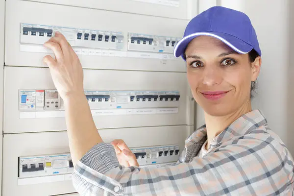 屋内ヒューズボードの近くに立っている幸せな女性電気技師 — ストック写真