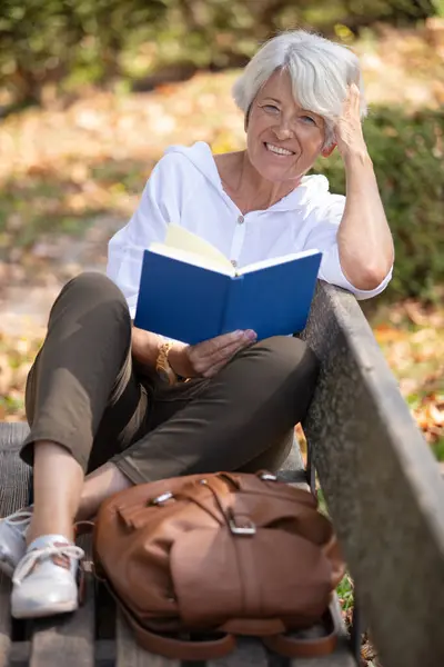 serious focused old lady reading novel in park