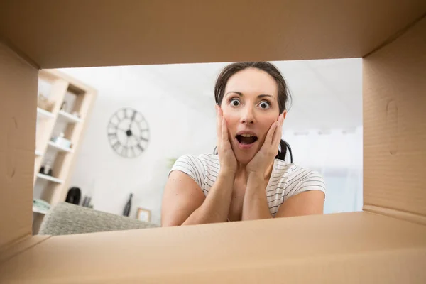 happy surprised woman opening a box looking into it