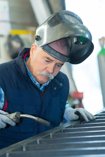 戴防护面罩的焊机修理汽车 免版税图库图片