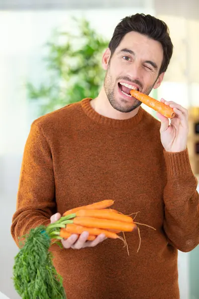 Homem Comendo Cenouras Cozinha Moderna — Fotografia de Stock
