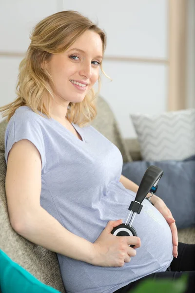 Pregnant Pleasant Woman Holding Headphones — Stock Photo, Image