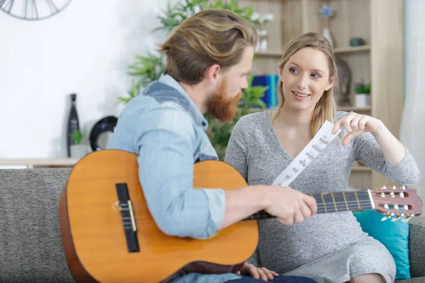 怀孕的女人给她男朋友的音乐弹吉他 — 图库照片