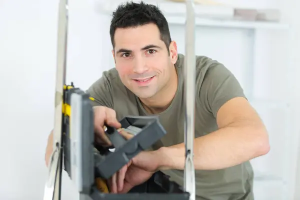 portrait of handyman seen through top of stepladder