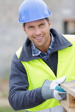 worker with wooden plank in hands at construction site clipart