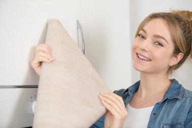 woman holding roll of veneer to revamp her kitchen cupboards clipart