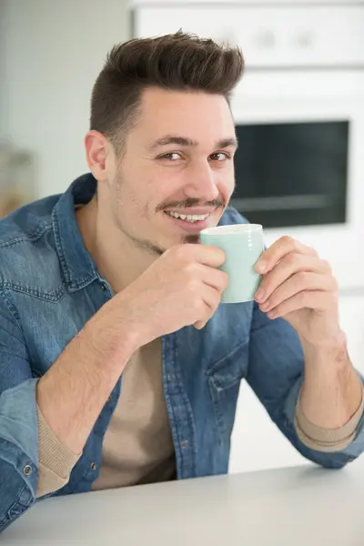 happy man having a cup of coffee in kitchen