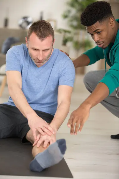 Medelålders Man Stretching Med Tränare — Stockfoto