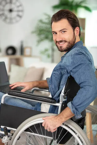 handsome young handicapped man in wheelchair working on laptop
