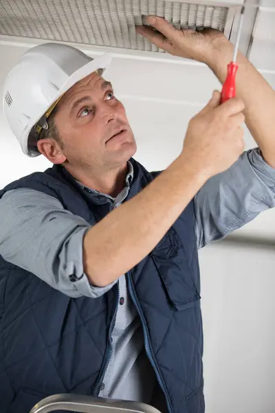 Mannelijke Werknemer Bevestigt Lamp Aan Het Plafond — Stockfoto