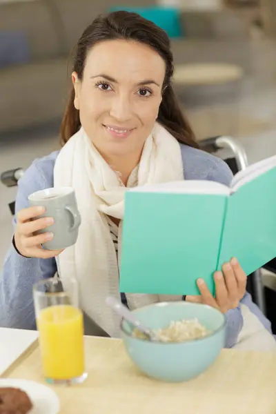 Senhora Livro Leitura Cadeira Rodas Enquanto Toma Café Manhã — Fotografia de Stock