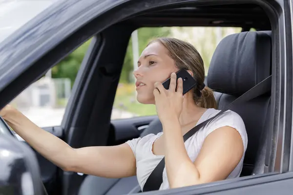 彼女の車を運転しながら携帯電話を使用している女性 — ストック写真