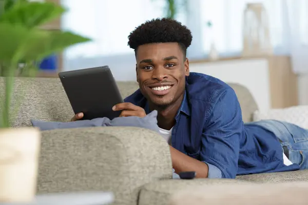 Junger Mann Auf Couch Mit Tablet Stockbild
