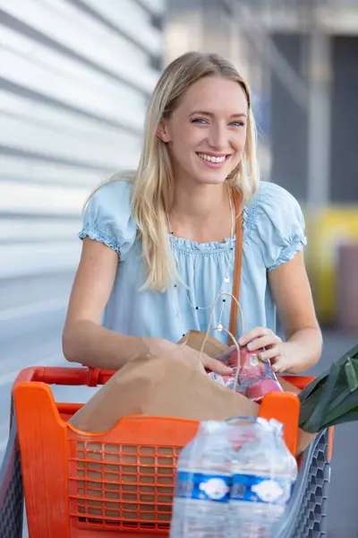 在超市门口停车的年轻女子 免版税图库图片