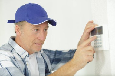 mature male worker installing alarm system clipart
