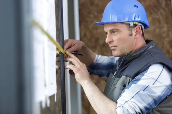 man measuring window prior to installation of roller shutter
