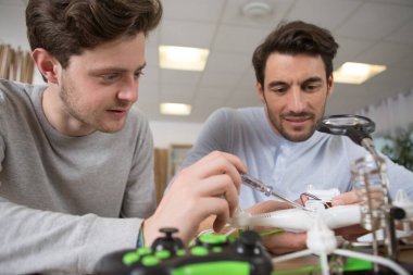 medium shot of a father and son repairing a drone clipart