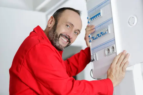 happy male electrician working on fusebox