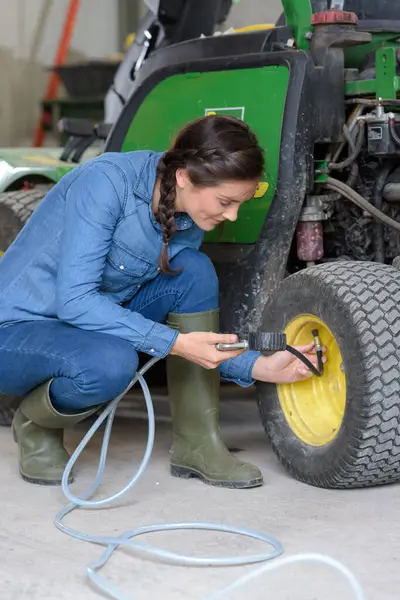 female agricultural mechanic checking air pressure on tire