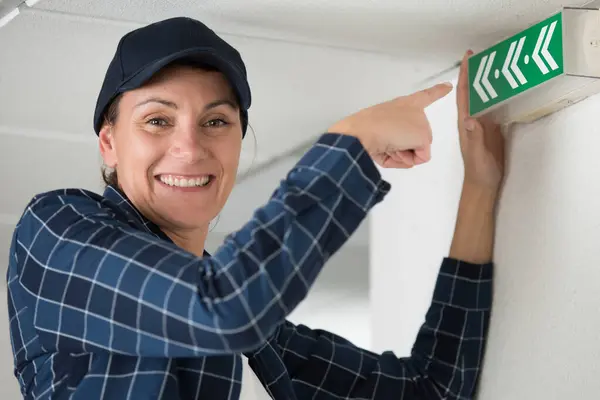Happy Woman Technician Pointing Exit Sign — Stock Photo, Image